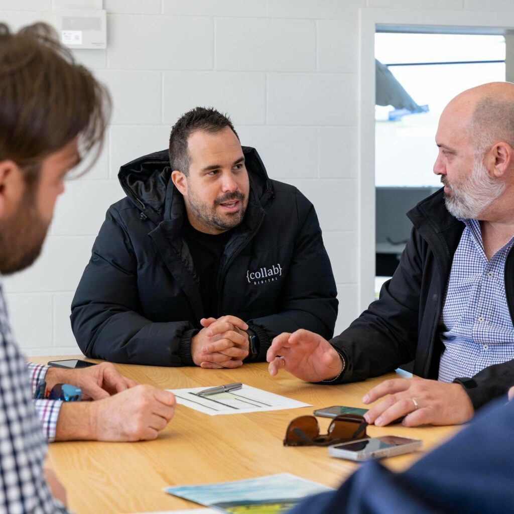 Brent Ireland talks to his team around a table