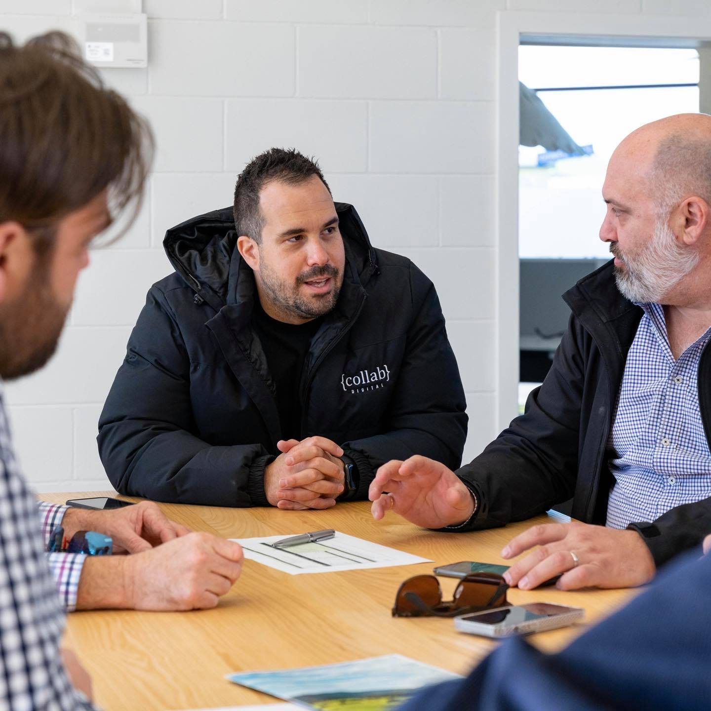 Brent Ireland talks to his team around a table