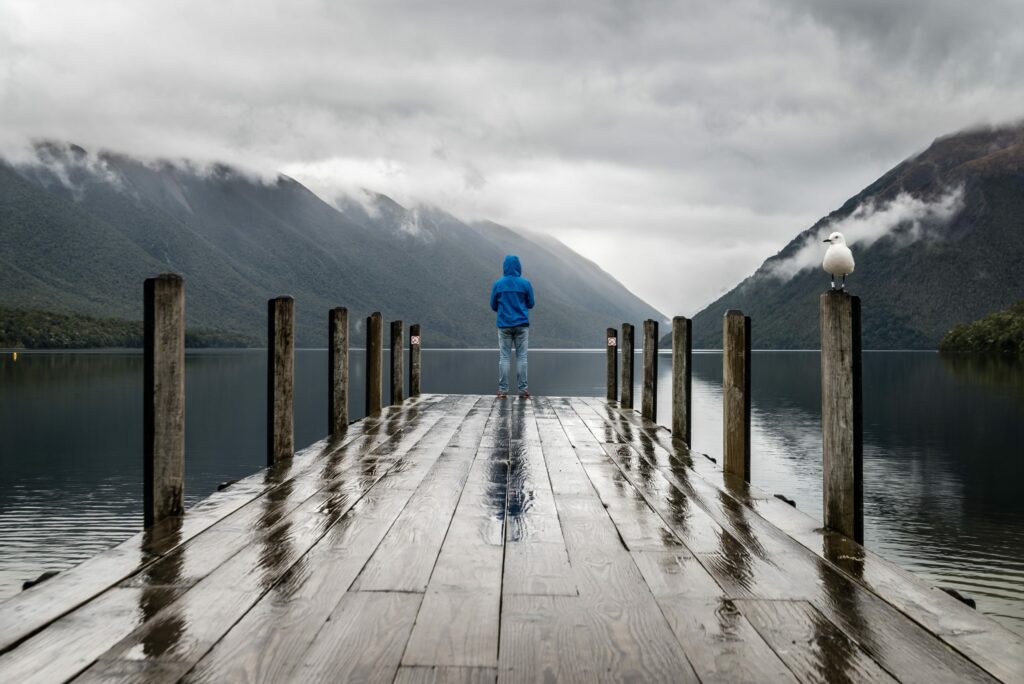 Person stands on lake edge at the edge of a jetty