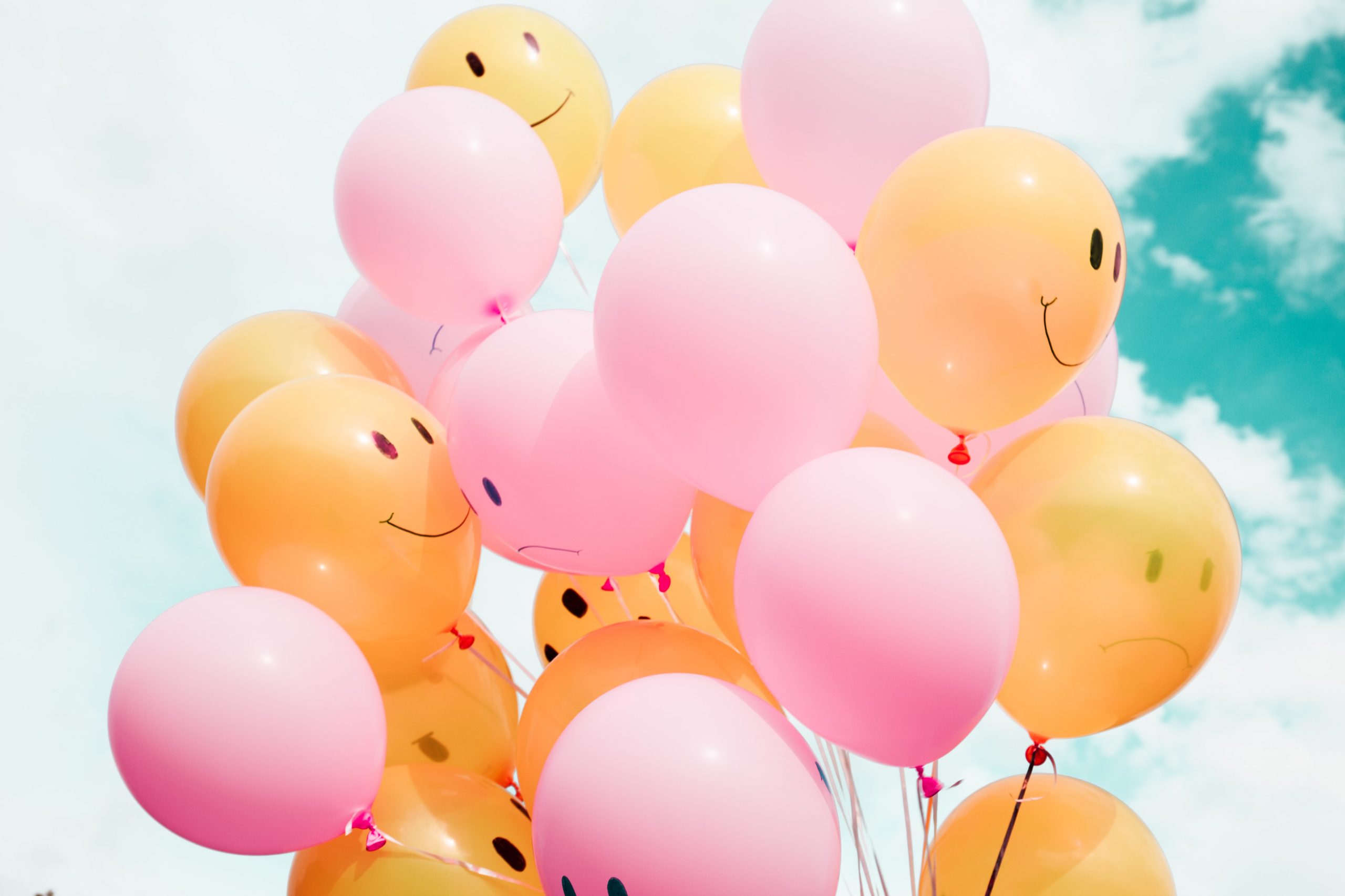 Pink and yellow balloons floating in the sky