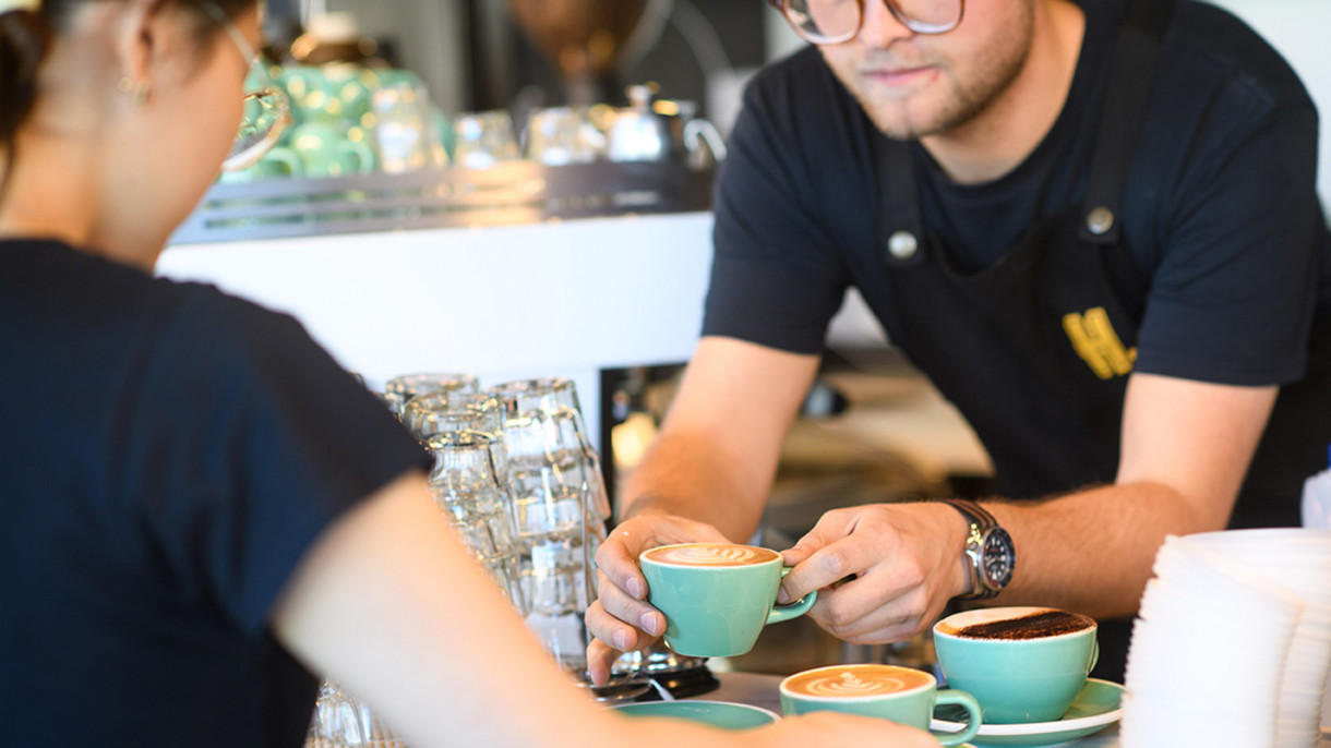 Barista passing a coffee to a patron
